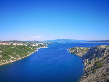 High angle view of sea and mountains against clear blue sky