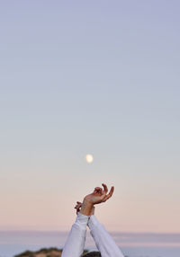 Man with arms raised against sky during sunset