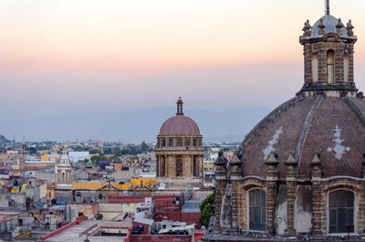 Churches in city against sky during sunset