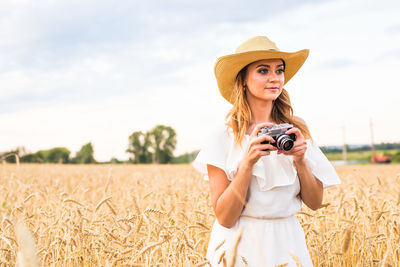 Young woman wearing hat standing on field