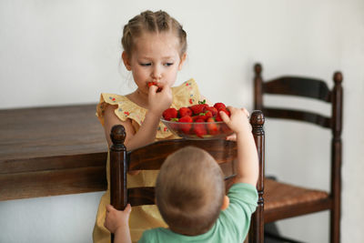 Two young girls eating strawberries in living room