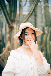 Portrait of young woman standing against blurred background