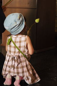 Rear view of girl in hat playing with toy at home