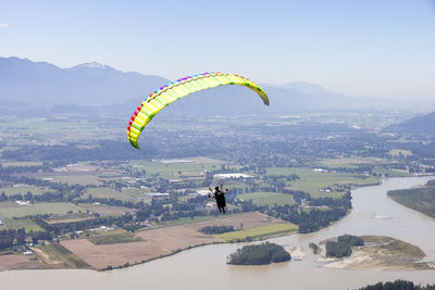 People paragliding over cityscape against sky