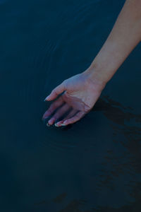 Cropped hand in lake