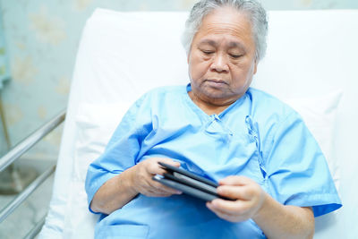 Man holding mobile phone while sitting on bed