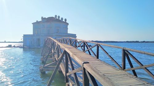 Bridge over sea against clear blue sky