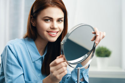 Portrait of smiling young woman holding camera