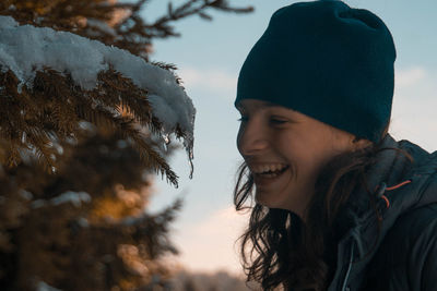 Portrait of smiling young woman against sky during winter