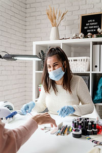 Young woman wearing glove and mask working at salon