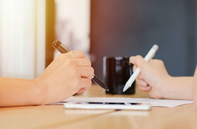Close-up of woman hand using mobile phone on table