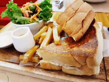 Close-up of a sandwich and vegetables on wooden board