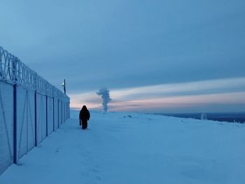 Rear view of person walking on snow covered landscape