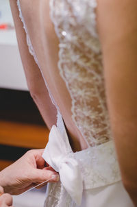Cropped hands of person tying bow for bride