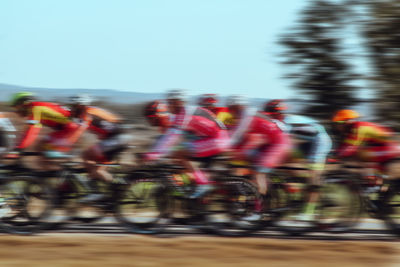 Blurred motion of people riding motorcycle against sky