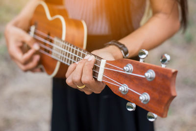 Midsection of woman playing guitar