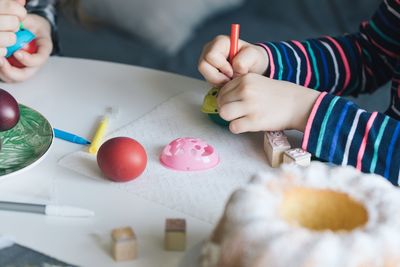 Close-up of girl holding multi colored pencils on table