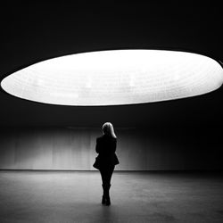 Full length rear view of woman standing below skylight