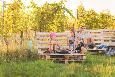 Family sitting on bench in vineyard