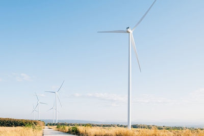 Windmills on field against clear sky