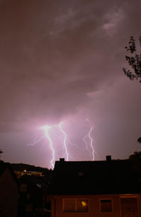 Illuminated cityscape against cloudy sky