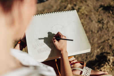 Young woman artist drawing in spiral notebook