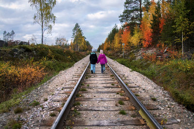 Rear view of man walking on railroad track