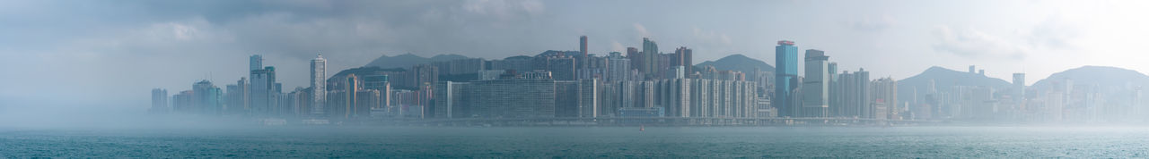 Panoramic view of buildings against cloudy sky