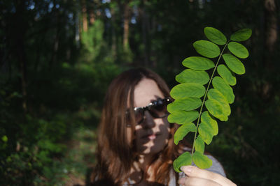 Portrait of woman holding leaves in tree