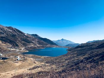 Scenic view of lake and mountains against clear blue sky