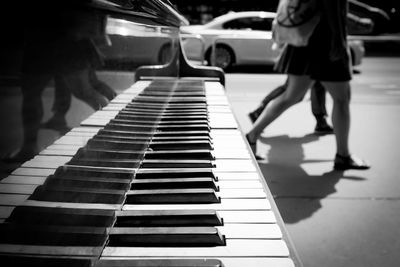 Low section of people walking by grand piano on sidewalk