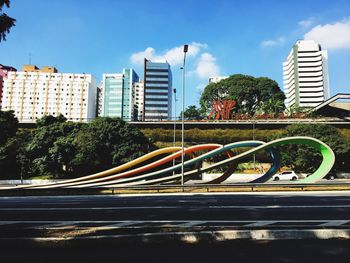 Road by buildings against sky in city
