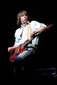 Young man playing guitar against black background