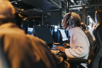 Senior women and men playing video game on computers at gaming center during weekend