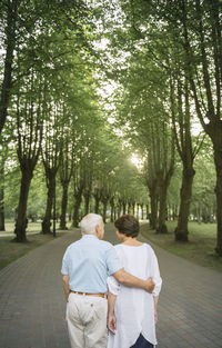 Back view of senior couple strolling in a park at sunset