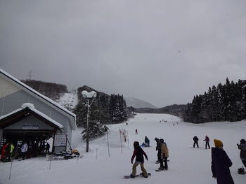 People walking on snow covered mountain against sky