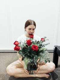 Portrait of young woman sitting on rose