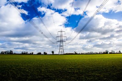 Electricity pylon on field against sky