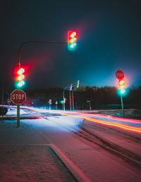 Stop light and light trail on the snow covered road at night