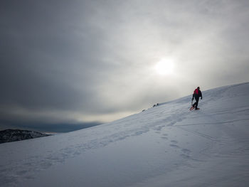 Man skiing on snowcapped mountain against sky