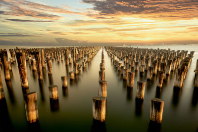 Panoramic view of wooden posts in sea against sky