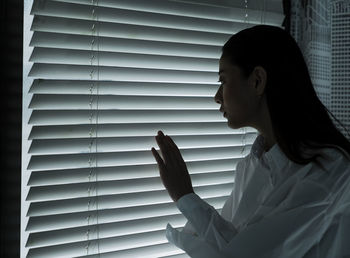 Side view of woman touching window