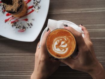 Midsection of woman holding coffee cup on table