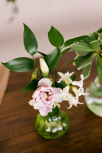 Pink eustoma flower and green branch with leaves in a green glass vase in the decor of the house