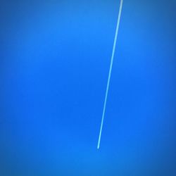 Low angle view of vapor trails against clear blue sky