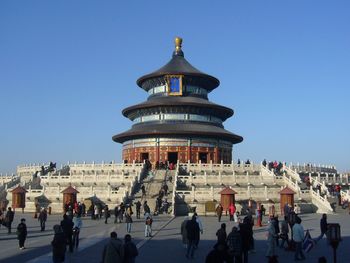 People at temple against clear blue sky