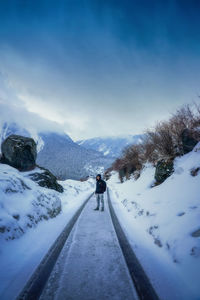 Man on snow covered road against sky