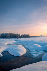 Scenic view of snow covered landscape against sky during sunset