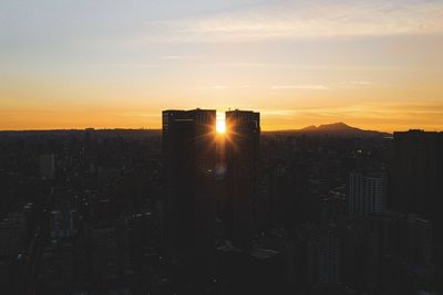 Modern buildings against sky during sunset in city