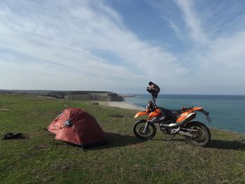 Man riding motorcycle on sea shore against sky